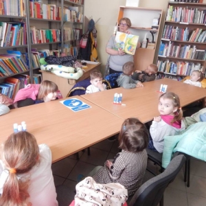 Budynek biblioteki w Szyszyńskich Holendrach, dzieci siedzą przy stołach, słuchają bajki.