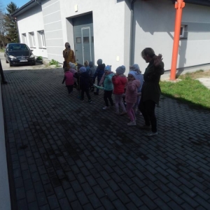 Dzieci wychodzą z biblioteki,, ustawione na placu w parach trzymają pluszowego węża. Machają na pożegnanie