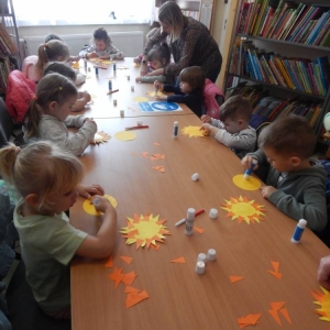 Grupa dzieci siedzi przy stole, wykonują słoneczka