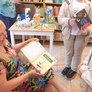 Agnieszka Frączek podpisuje w  bibliotecezakupione przez dzieci książki