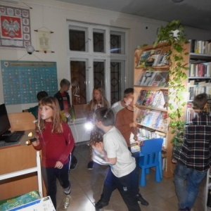 Dzieci z latarkami biegają po bibliotece